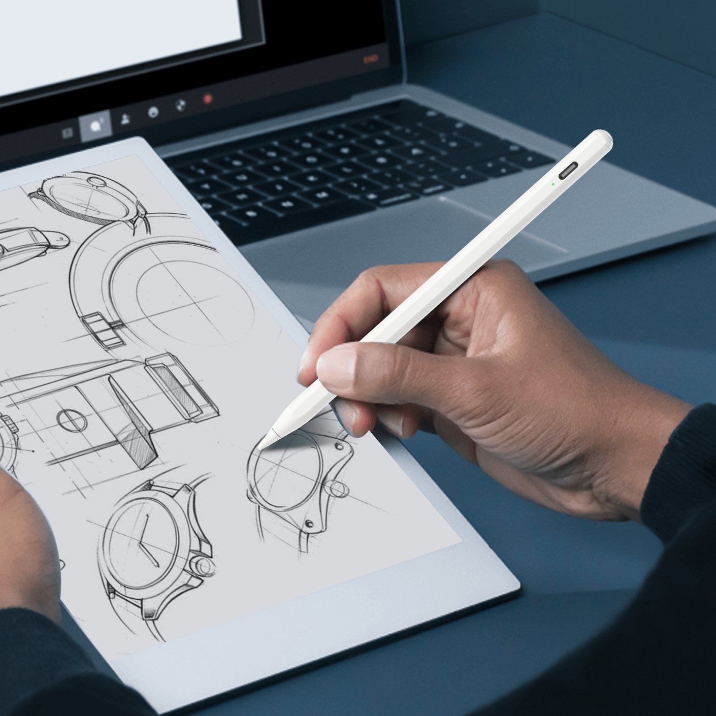 A designer sketching watch parts with an OASO stylus beside a laptop